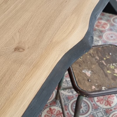 Détail du bord naturel brûlé d’une table en chêne massif avec pieds en X